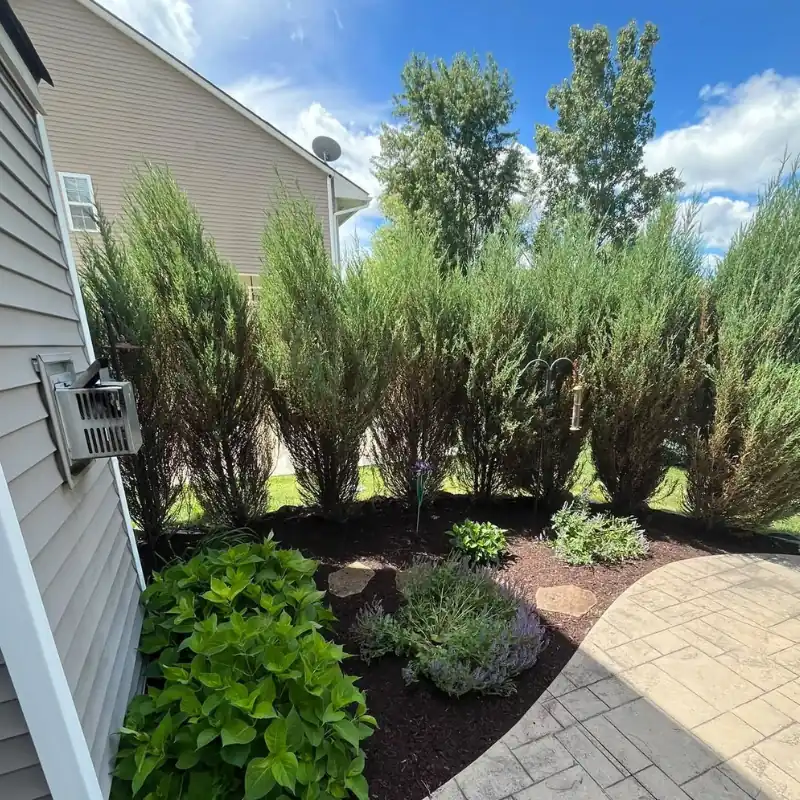 Residential landscaping with shrubs, flower bed, and patio by Legacy Lawn And Landscape